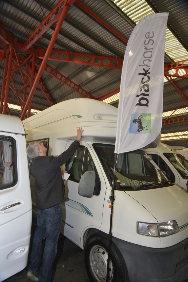 Potential buyer inspects the exterior of a used motorhome