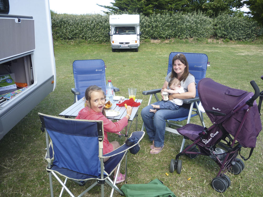 Garden chairs and tables near a campervan