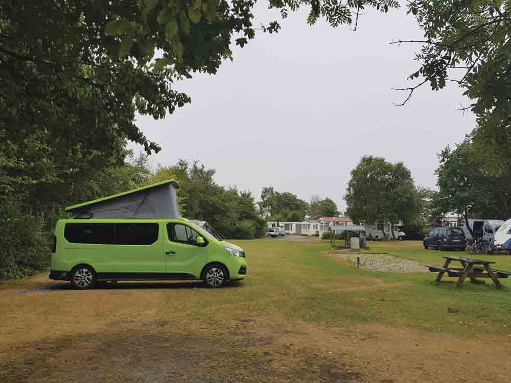 Image of a green campervan parked at Beleef Lauwersoog campsite