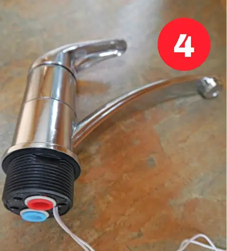 The replacement tap showing colour-coded blanking plugs for hot and cold pipes.