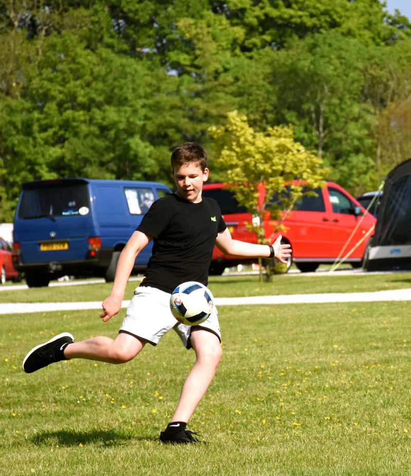 teenager playing football at campsite