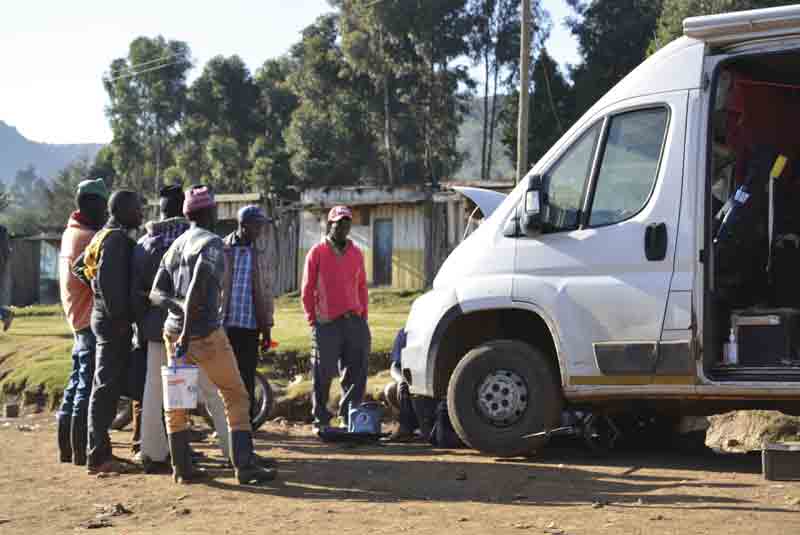 Herders and crowds of people surrounding a campervan