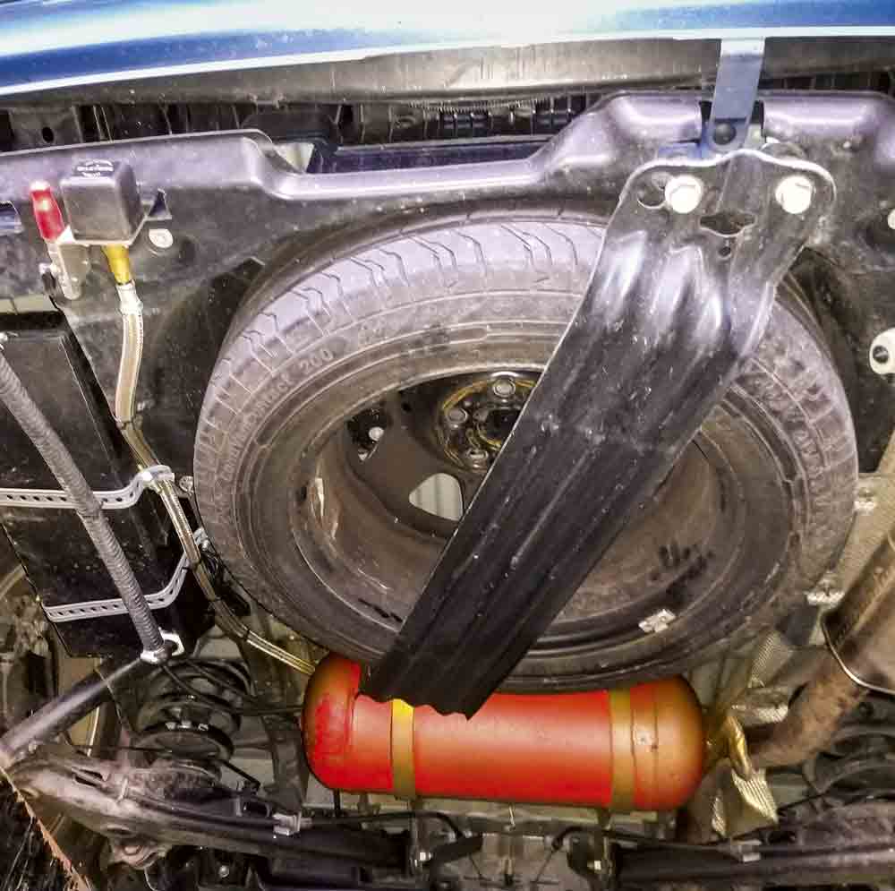 Gas tank being fitted in front of the campervan’s spare wheel