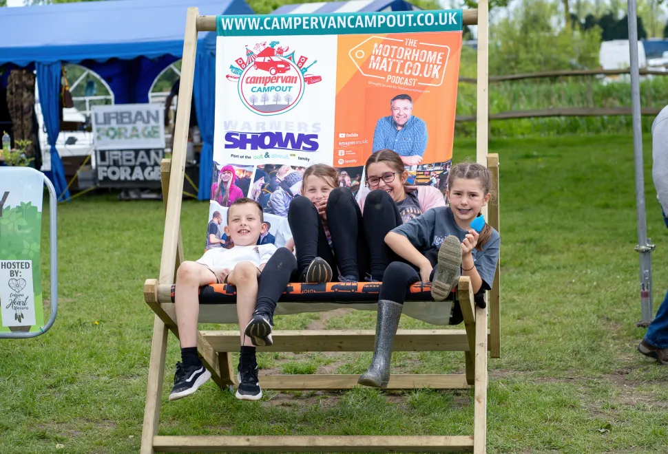Young family relaxing in a giant deckchair at Campervan Campout Festival