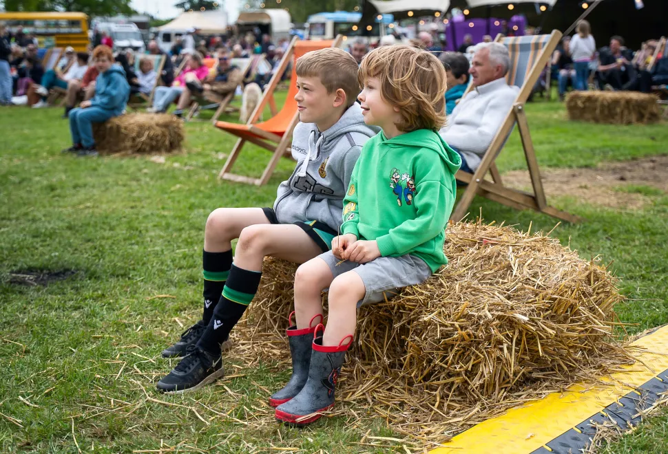 Young festival attendees sat on a hay bales enjoying the music at Campervan Campout Festival