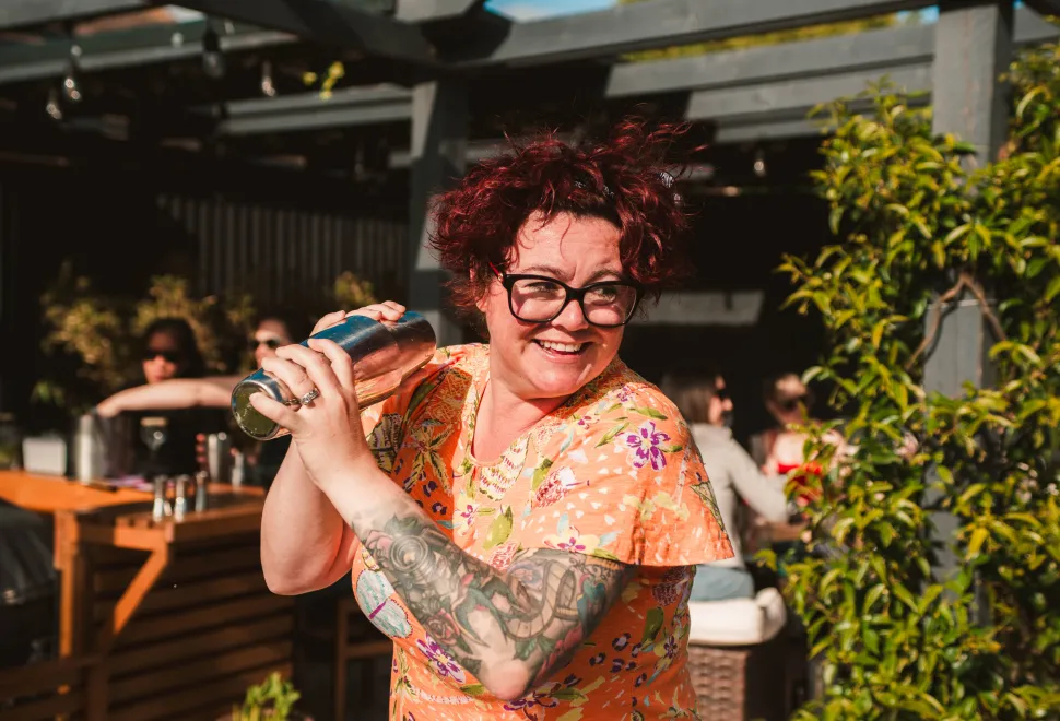 woman making a cocktail with a shaker