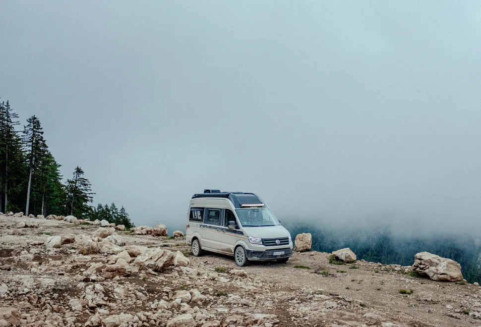 Carado CV595 on an unpaved road on a mountain with low clouds behind