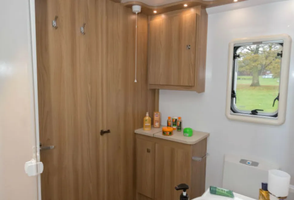 Under-a-hinged-lid-on-top-of-the-cabinet-in-the-corner-is-a-linen-bag-is-suspended-on-four-hooks-87586