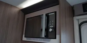 A-mirror-fronted-microwave-set-into-a-cabinet-with-light-above-it-08005
