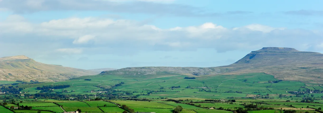 Whernside and Ingleborough high above the green farmland