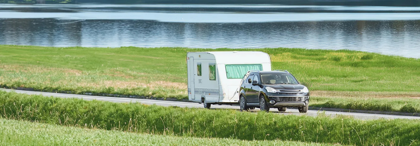 Car towing a camper on a sunny day