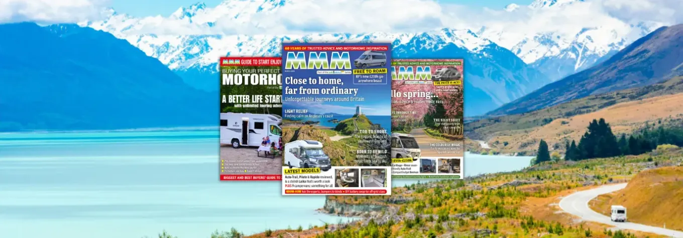 Three Motorhomes magazine covers stacked in the center, set against a scenic mountain road and lake landscape, highlighting road trip inspiration.
