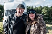 Johnny Vegas standing outside a vintage motorhome at a glamping site