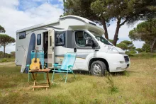 image of a motorhome set up in a field with deck chairs outside