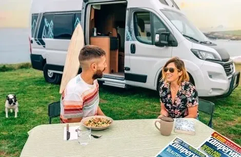 image of two people sitting outside a campervan