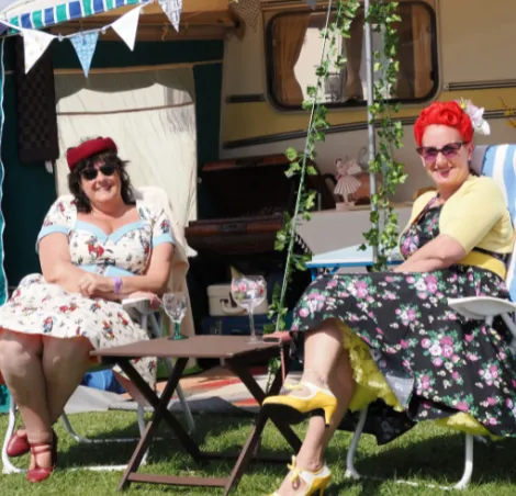 Two ladies sitting in front of their classic caravan 