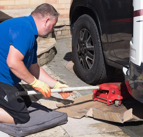 Mechanic using trolley jack  to lift a motorhome front wheel