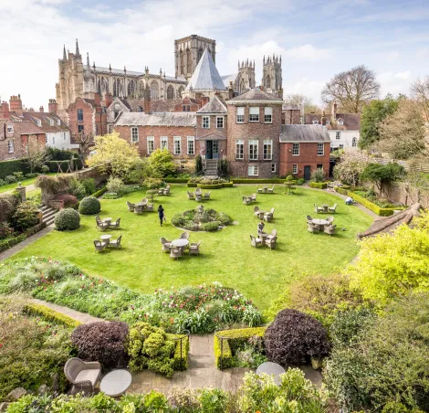 YORK, UK - April 17, 2023. Gardens of Grays Court Hotel with York Minster in the background, viewed from York city walls. York, UK