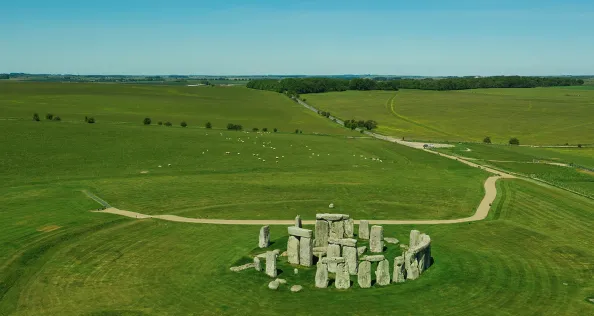 Aerial view of Stonehendge on a sunny day in summer with no people around. This is a historic site with a ring of standing stones, it was believed to be a burial site. Blue sky and space for text.
