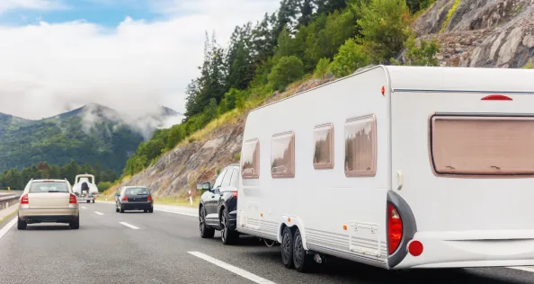 Scenic view big modern white family rv camper van vehicle drive Europe highway road alpine mountain cloud in summer day. Rving motorhome lifestyle travel and adventure tourism trip journey concept