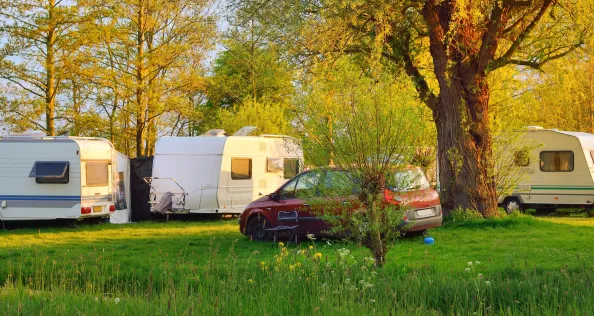 Caravan and a car parked on a green lawn in a camping site. Idyllic spring landscape. Holland. RV, transportation, road trip, vacations, ecotourism, travel, lifestyle, recreation